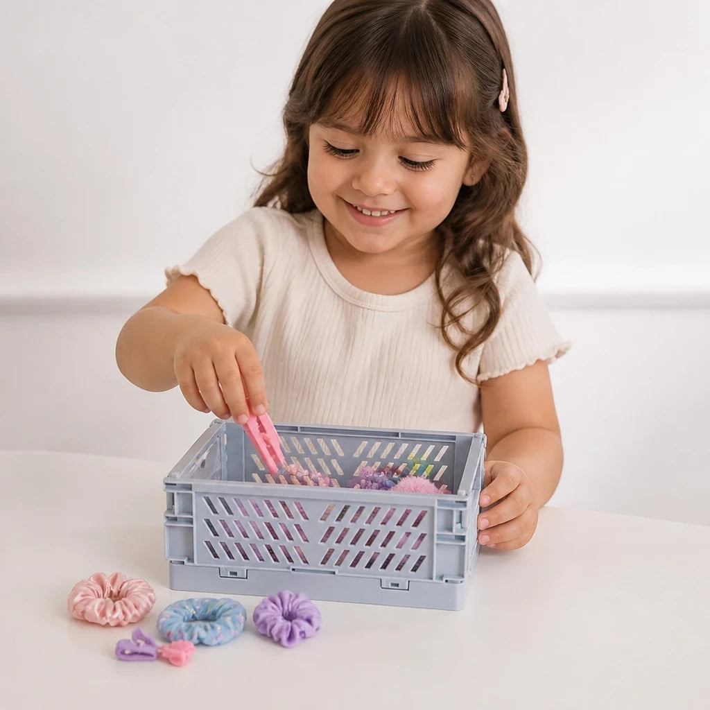 Menina organizando acessórios em organizador de brinquedos dobrável em plástico resistente, prático e seguro, ideal para pais