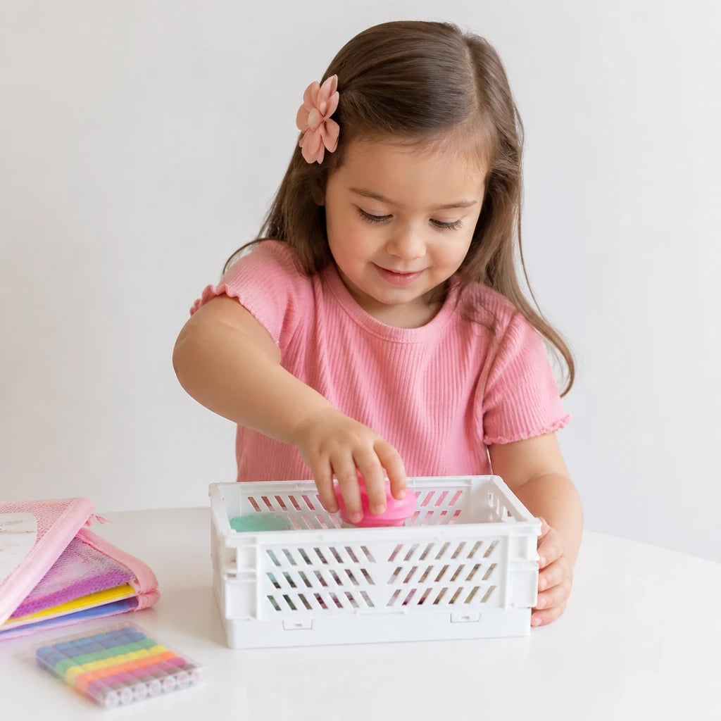 Menina guardando brinquedo em organizador de brinquedos dobrável de plástico resistente, prático e seguro ideal para pais