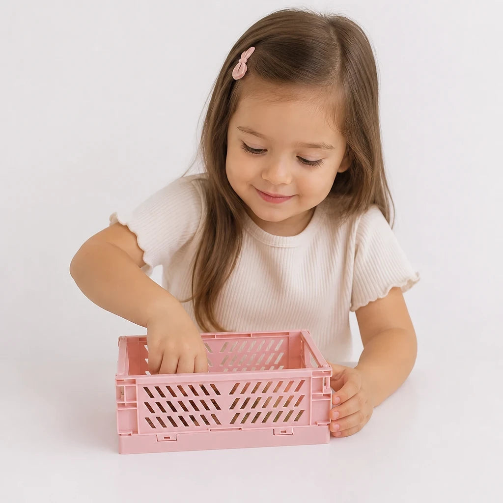 Criança guardando itens no organizador de brinquedos dobrável rosa em plástico resistente, prático e seguro para pais e avós
