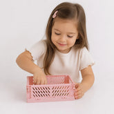 Criança guardando itens no organizador de brinquedos dobrável rosa em plástico resistente, prático e seguro para pais e avós